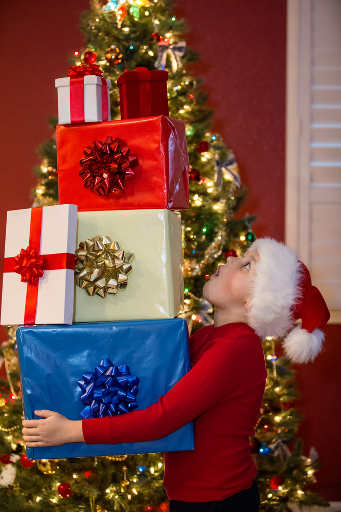boy holding stack of Christmas presents