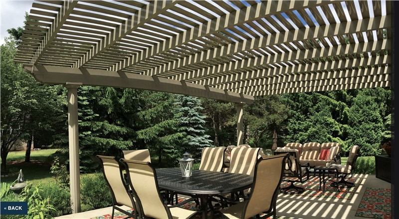 A pergola over a table and chairs on a sunny day